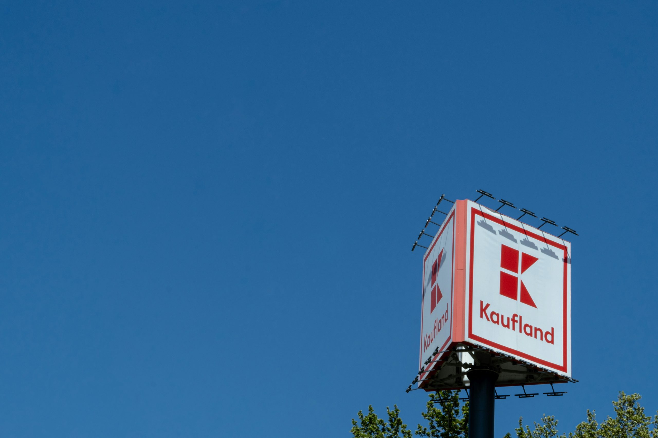Ein wolkenfreier, blauer Himmel, in der unten linken Ecke die Spitze eines Turms, auf dem Kaufland steht