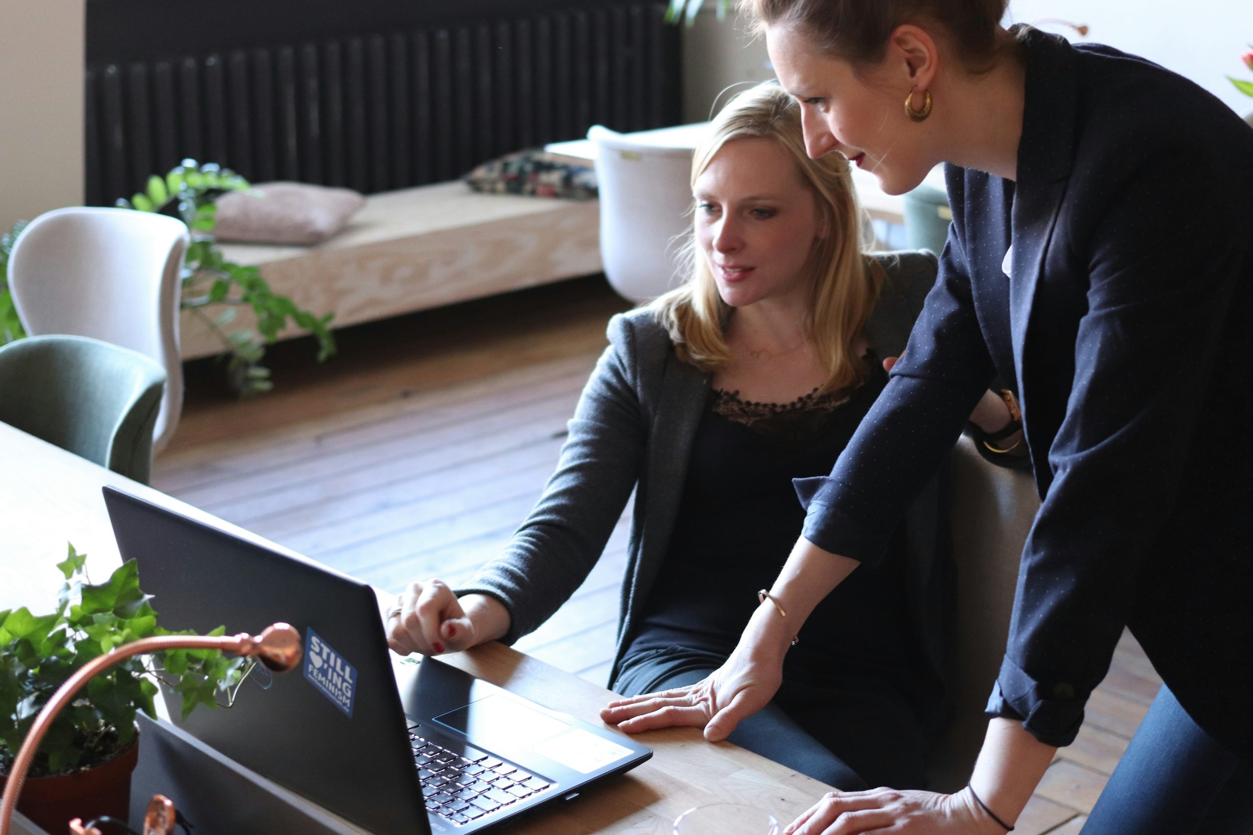 Zwei Frauen diskutieren ruhig vor einem Laptop in einem Büro