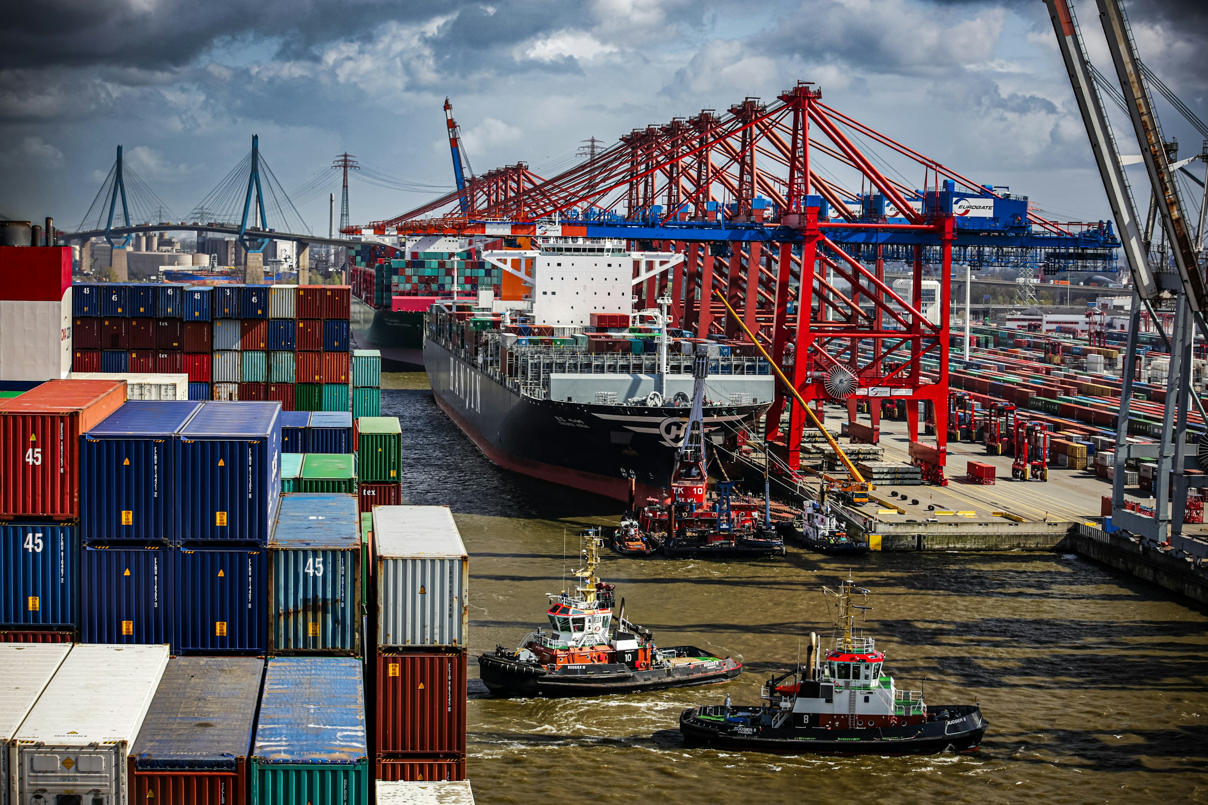ein-schlepper-im-wasser-neben-einem-grossen-frachtschiff-und-containern