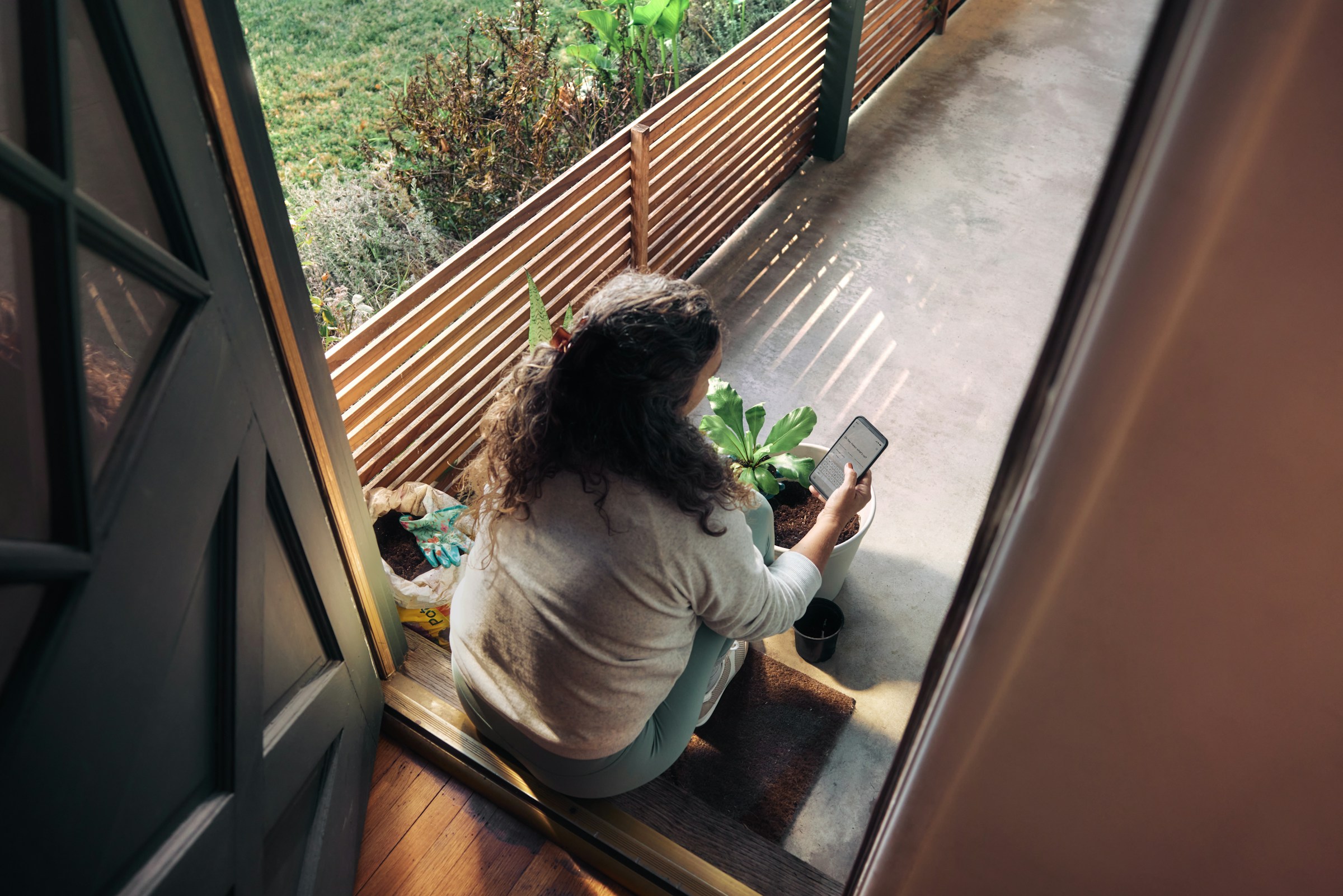 frau-sitzt-auf-dem-balkon-mit-smartphone