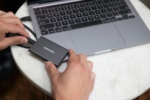 eine-person-die-einen-laptop-und-ssd-halt